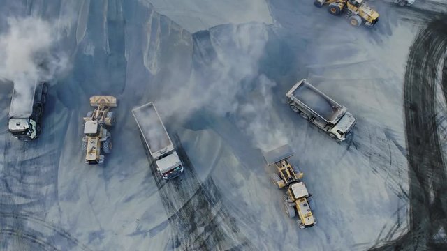 AERIAL. Top angle view of big career and excavators pours sand into the truck. On the construction site top view. Shooting from the drone.