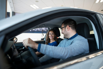 Young couple testing new vehicle they want to buy. Car dealer.