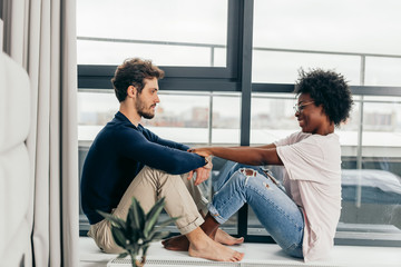 Romantic mixed race affectionate young newlyweds relax at modern hotel interior while vising foreign country in vacation