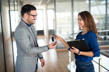 Car dealer handing over keys to the vehicle buyer. Successful car purchase.
