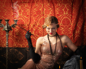 Girl in an evening dress with a cigarette. Studio retro style photo