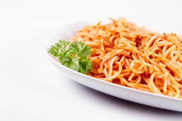 Spaghetti with pesto rosso decorated with parsley on a white background