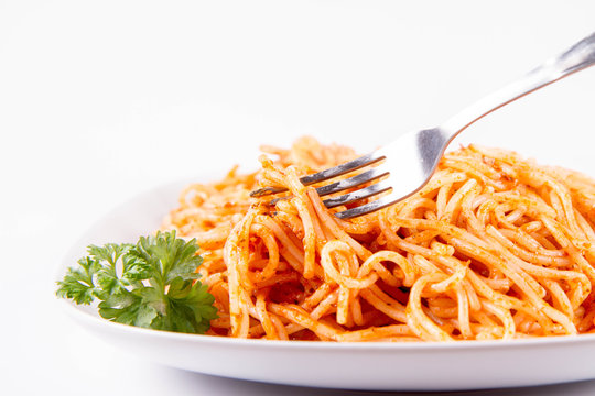 Spaghetti with pesto rosso decorated with parsley  on a white background