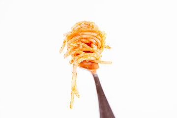Spaghetti with pesto rosso on a fork on a white background