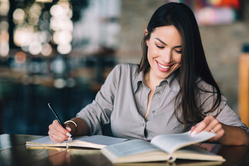 Young woman holding book and pencil for taking notes