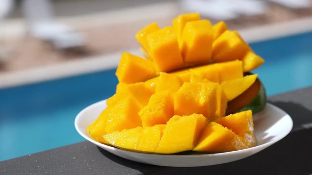 Half cutted cubes slices ripe mango on poolside background, nobody
