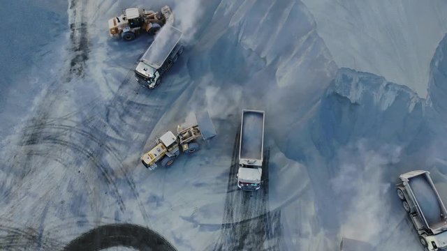 AERIAL. Top angle view of big career and excavators pours sand into the truck. On the construction site top view. Shooting from the drone.