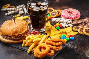 Fotobehang Junk food concept. Unhealthy food background. Fast food and sugar. Burger, sweets, chips, chocolate, donuts, soda. © vaaseenaa