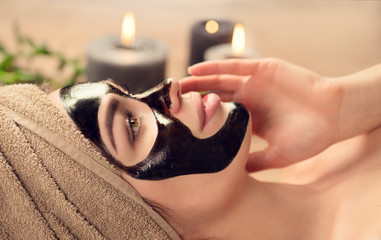 Beautiful woman with black purifying black mask on her face. Beauty model girl with black facial...