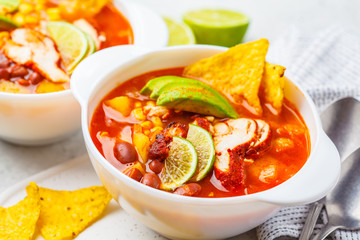 Mexican soup (Chili con carne) with beans, chicken, corn and nachos in white bowls - traditional mexican food.