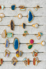 A lot of rings jewelery in different colors and gems on a plate in jewelery ring gallery. Rings with large gems in the window. Rings with different stones. vertical photo.