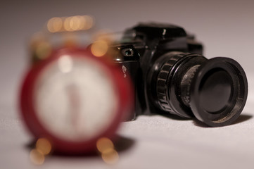 Close-up of a small camera in the background and a clock in the foreground