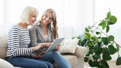 Mature mother and adult daughter with digital tablet
