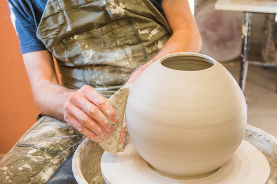     Manual worker in the workshop sculpting ceramic vase. Hands closeup detail. Small artistic craftsmen business concept. 