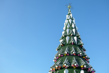 City Christmas tree against a blue sky. Christmas Garlands. Weekends and holidays