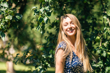 Happy woman with beautiful blonde hair smiling in the summer park