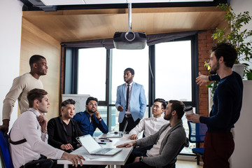 Businessman in blue formal suit standing and leading business meeting. Male chief executive putting his ideas during presentation in boardroom.