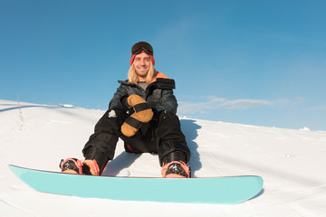 Fototapeta na wymiar smiling positive sportsman looking at the camera. good day for snowboarding.man rejoicing at useful unforgettable weekends.low view photo