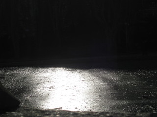 hielo e estanque a contraluz con efecto brillo de agua, cristales en fractura y hojas, tras noche de heladas