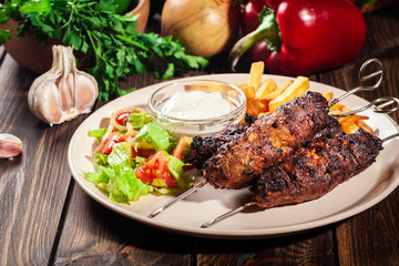 Grilled shish kebab served with fried chips and salad