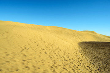 Beautiful yellow sand dunes against the blue sky. Natural background.