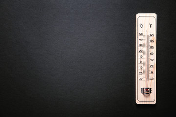Wooden thermometer on black background.