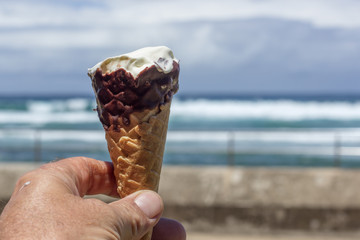 mans hand holding a half eaten ice cream at the beach 