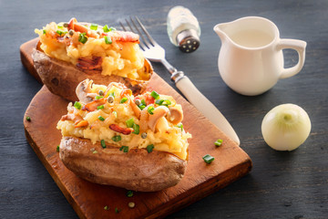 Baked potatoes with bacon and mushrooms in a rustic way on a wooden board. Close-up.