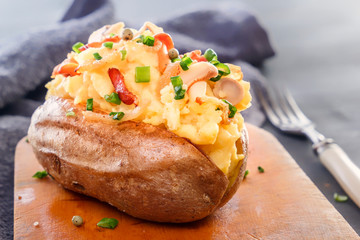 Baked potatoes with bacon and mushrooms in a rustic way on a wooden board. Close-up. Copy space