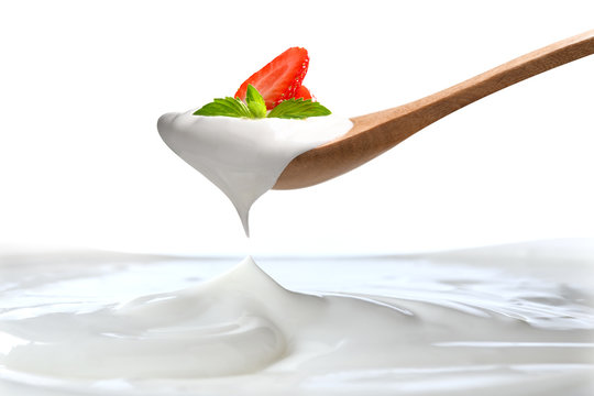 Plain Yogurt On A Spoon With Fresh  Strawberry On Top Hanging Above Of Plain Yogurt Isolated On White Background