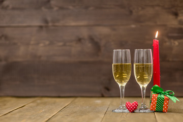 Pair glass of champagne, gift boxes with candles. Wooden background with empty space for text