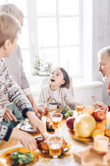 curious cute girl is talking with her relatives while havving dinner. close up cropped photo