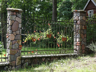 Vicinities of Svetlogorsk. A fencing fragment from the forged metal rods and columns trimmed with a stone.