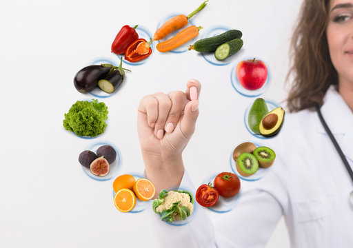 Hand of nutritionist doctor showing pill on symbols fruits