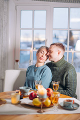 handsome guy is kissing his adorable girlfriend while sitting at the table. relationship, family, warm feeling , close up shot