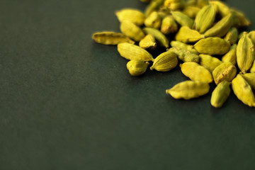 Close up on green cardamon seeds, selective focus, dark green background, selective focus