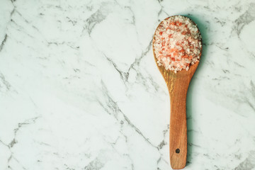 Fototapeta na wymiar Wooden kitchen spoon with Himalayan salt, white marble background, selective focus, free copy space
