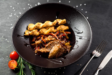 A meat dish with bread sticks and spices on black background