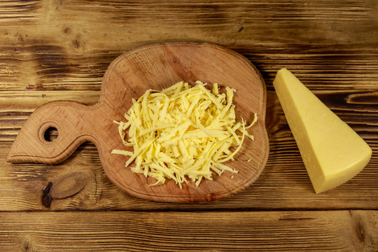 Grated cheese on cutting board on wooden table