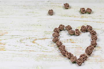 Heart made from brown roses. On wooden background, photo bokeh. Feast of love, Valentine's Day. Postcard with copy space.