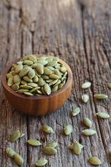 Pumpkin grain in wooden bowl on classic wooden table background, cereal