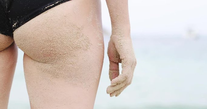 Sandy woman buttocks on the beach background.