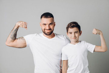 positive man and little boy with raised arms are posing to the camera. close up shsot.wellness,...