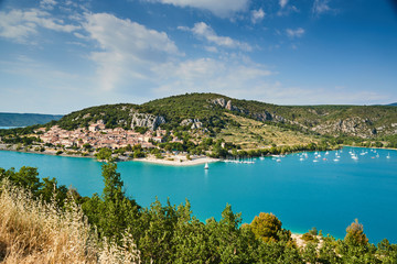Fototapeta na wymiar The city on the bank of the artificial lake in France, Provence, lake Saint Cross, gorge Verdone, azure water of the lake and slopes of mountains on a background, small boats, vacations place