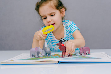 Little happy girl baby gets acquainted with the wild world of animals through the game, studying...