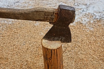 one old steel ax and a brown wooden log on sawdust