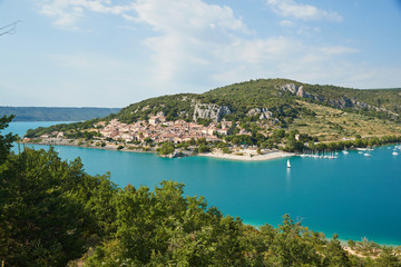 Naklejka na ściany i meble The city on the bank of the artificial lake in France, Provence, lake Saint Cross, gorge Verdone, azure water of the lake and slopes of mountains on a background, small boats, vacations place