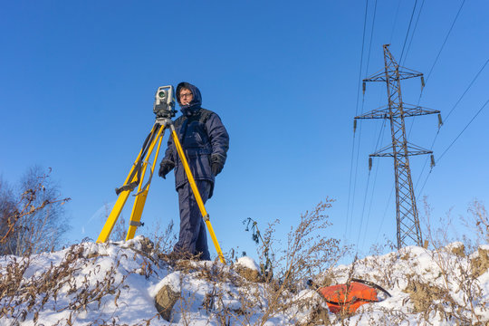 Surveyor in the winter on the construction site conducts topographic and cadastral work