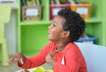 African American ethnicity kid smiling at library in kindergarten preschool classroom.happy...