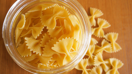 Pasta in the form of bows scattered from glass jar. Italian handmade pasta